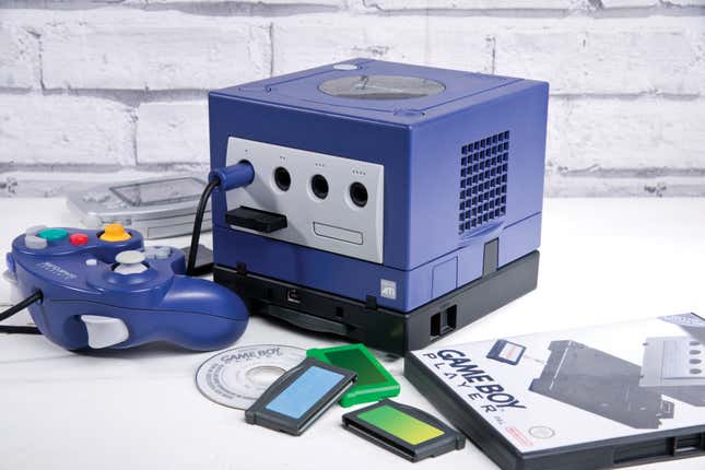 A Nintendo GameCube console is surrounded by a controller and a Game Boy player adapter. 